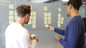 Deux professionnels organisent un projet avec des notes adhésives sur une paroi vitrée