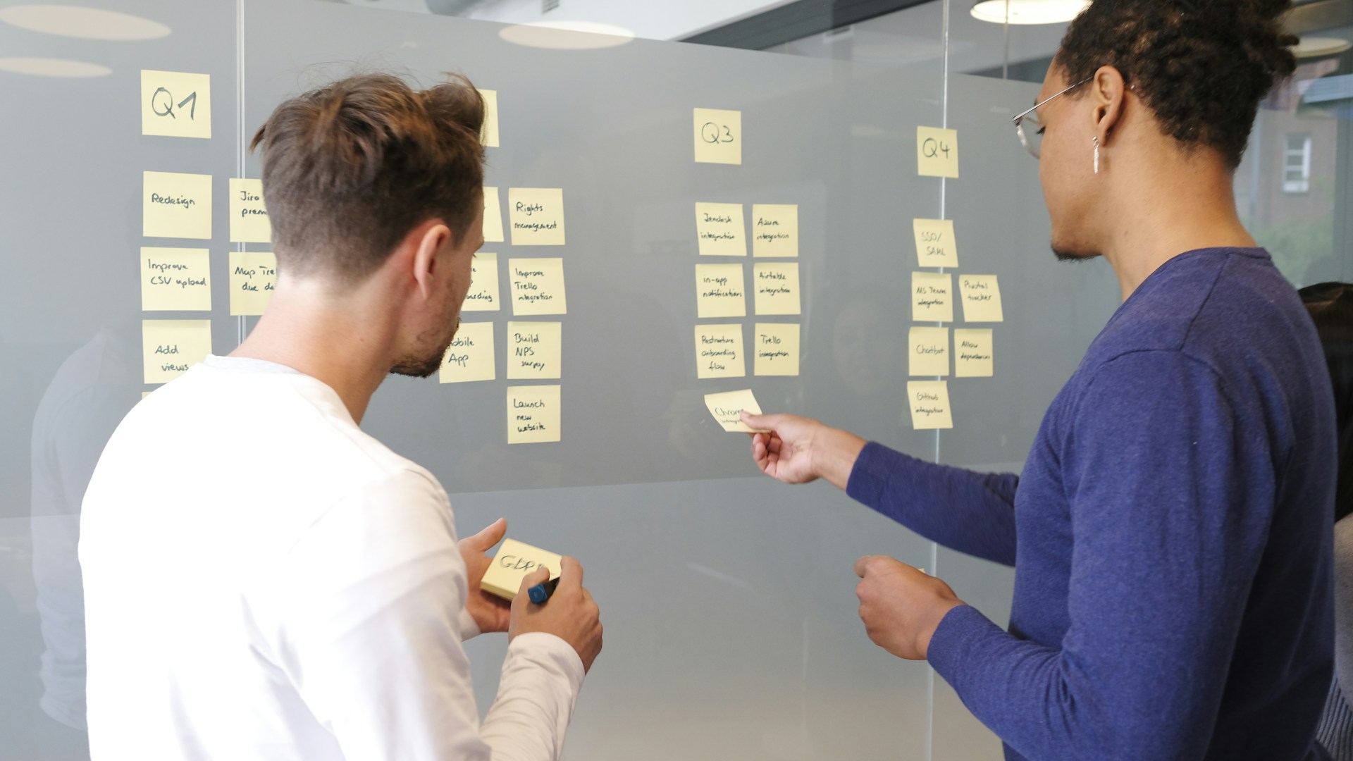Deux professionnels organisent un projet avec des notes adhésives sur une paroi vitrée